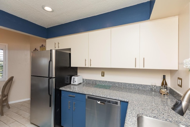 kitchen with blue cabinets, sink, white cabinetry, stainless steel appliances, and light stone countertops