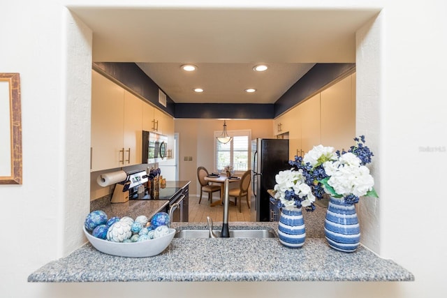 kitchen with appliances with stainless steel finishes, hardwood / wood-style flooring, light stone counters, and cream cabinets