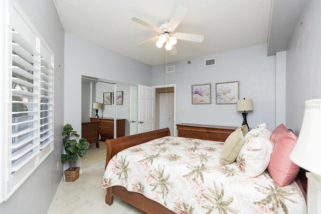 bedroom featuring light wood-type flooring, ceiling fan, a closet, and a textured ceiling