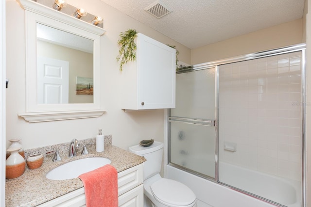 bathroom featuring a textured ceiling, toilet, bath / shower combo with glass door, vanity, and visible vents