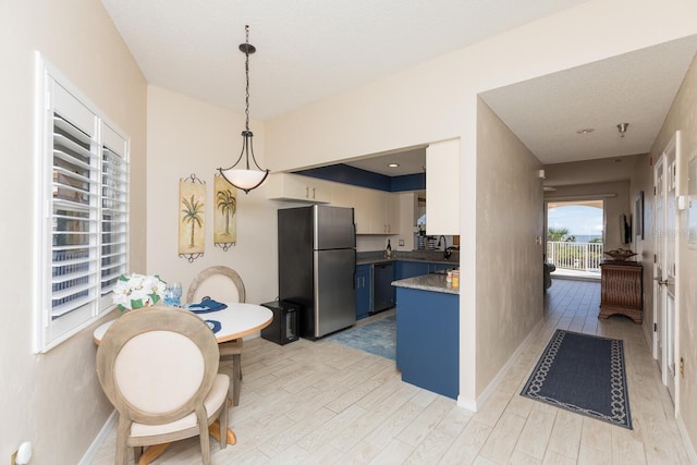 kitchen featuring baseboards, freestanding refrigerator, hanging light fixtures, light wood-type flooring, and blue cabinetry