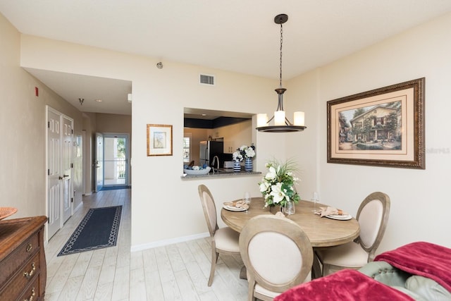 dining room featuring light wood finished floors, visible vents, and baseboards