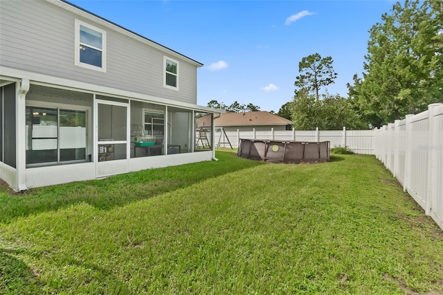 rear view of property with a sunroom, a fenced in pool, and a lawn