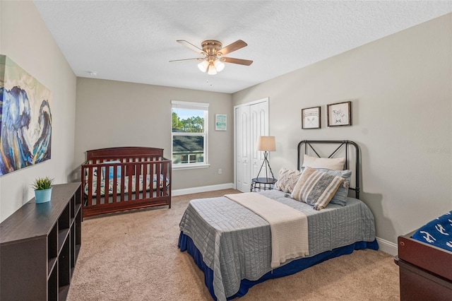 bedroom featuring a closet, a textured ceiling, light colored carpet, and ceiling fan