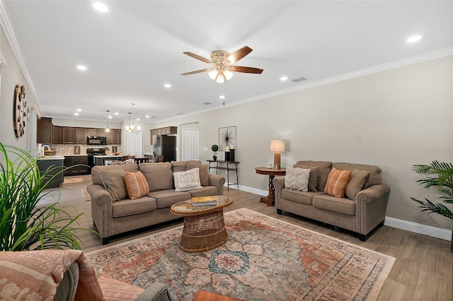 living room featuring crown molding, light hardwood / wood-style floors, and ceiling fan with notable chandelier