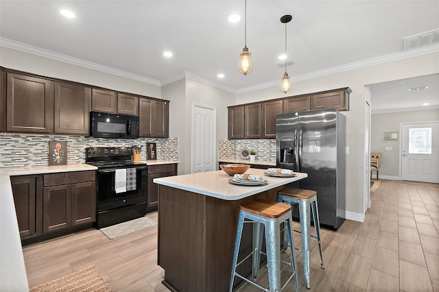 kitchen featuring hanging light fixtures, dark brown cabinets, a kitchen island, black appliances, and ornamental molding