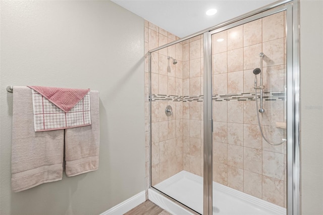 bathroom with a shower with shower door and wood-type flooring