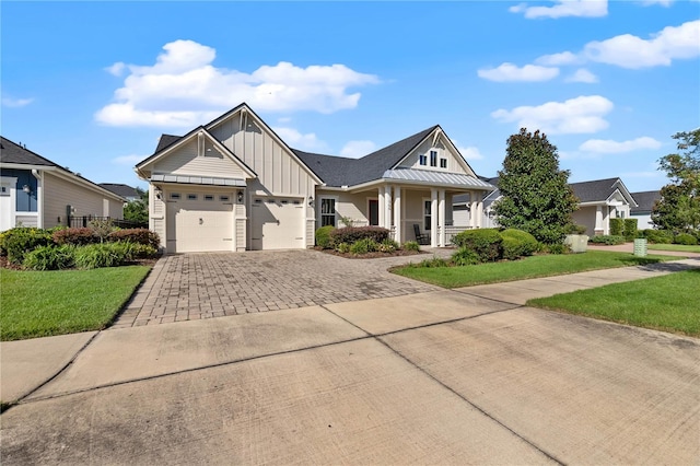 craftsman house with a garage, covered porch, and a front lawn