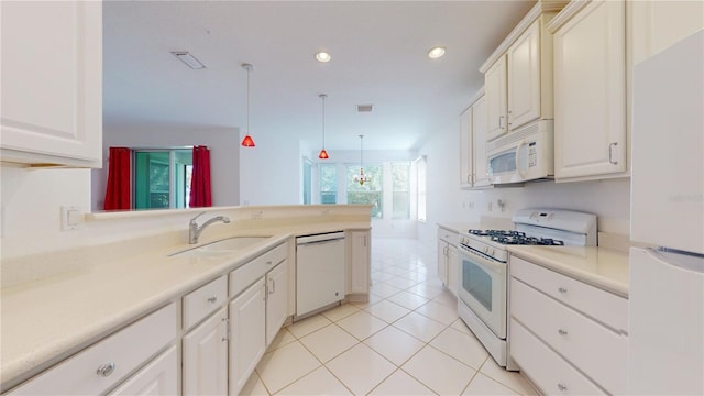 kitchen with sink, kitchen peninsula, decorative light fixtures, white appliances, and light tile patterned floors