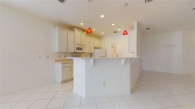 kitchen featuring kitchen peninsula, pendant lighting, white appliances, a breakfast bar area, and light tile patterned flooring