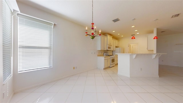 kitchen with white appliances, decorative light fixtures, a healthy amount of sunlight, and a breakfast bar area