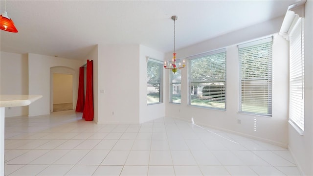 unfurnished dining area featuring light tile patterned flooring and an inviting chandelier