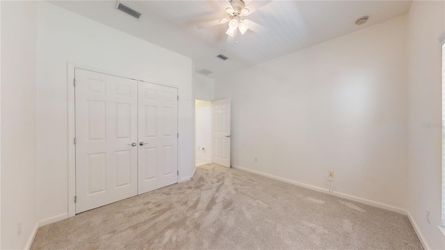 unfurnished bedroom with a closet, light colored carpet, and ceiling fan