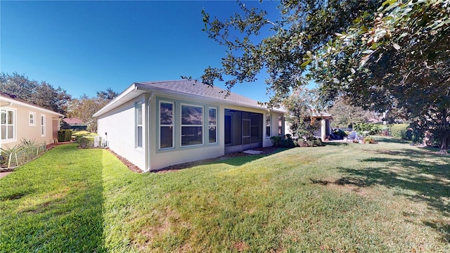 rear view of house featuring a yard and a sunroom