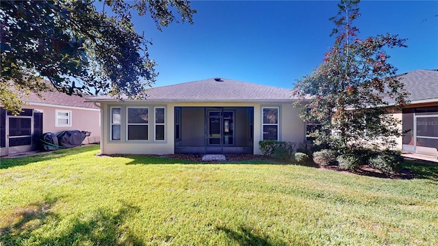 view of front of property with a shingled roof, a front yard, and stucco siding