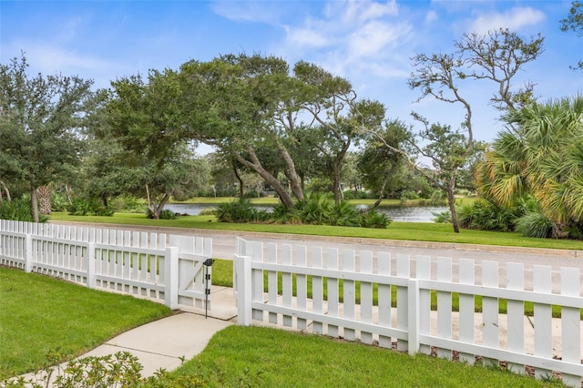 view of gate featuring a water view and a lawn