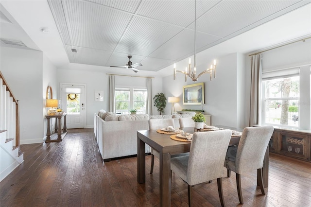 dining area with ceiling fan with notable chandelier and dark wood-type flooring