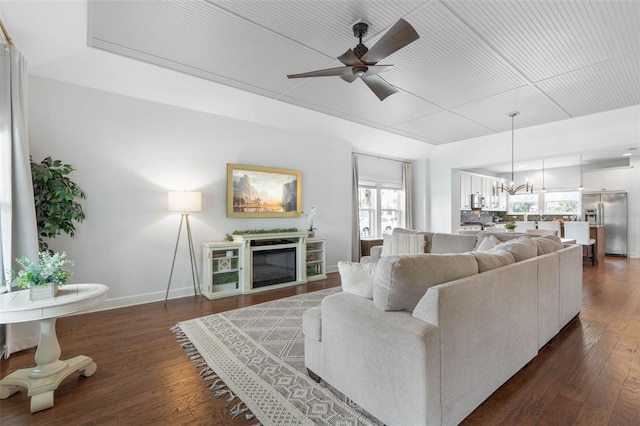 living room featuring ceiling fan with notable chandelier and dark hardwood / wood-style flooring