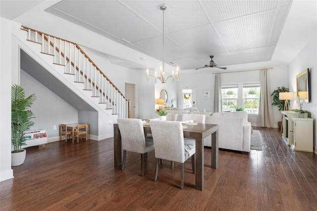 dining area featuring ceiling fan with notable chandelier and dark wood-type flooring