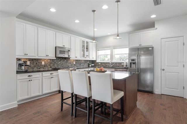 kitchen with dark hardwood / wood-style floors, white cabinetry, a center island, and stainless steel appliances