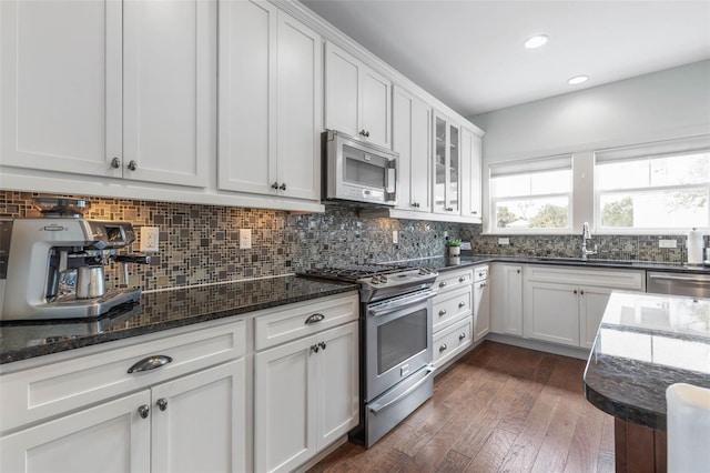 kitchen with sink, white cabinetry, appliances with stainless steel finishes, dark hardwood / wood-style flooring, and decorative backsplash