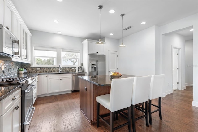 kitchen featuring white cabinets, sink, dark wood-type flooring, stainless steel appliances, and a center island