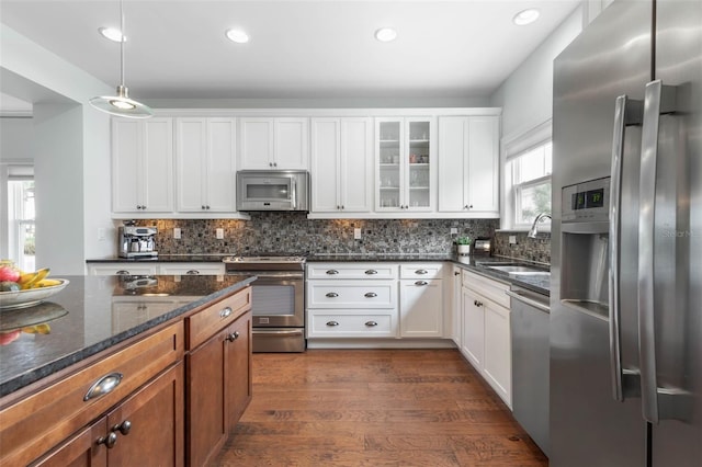 kitchen with dark stone countertops, a healthy amount of sunlight, white cabinetry, and stainless steel appliances