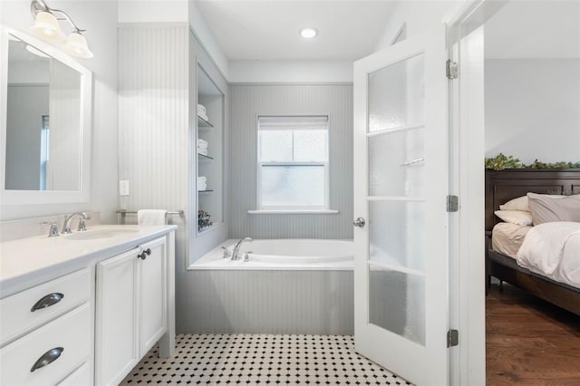 bathroom with a bath, vanity, and wood-type flooring