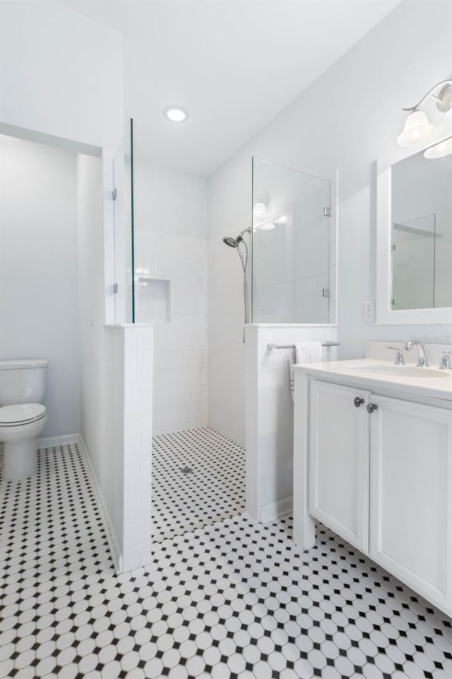 bathroom featuring vanity, tiled shower, and toilet