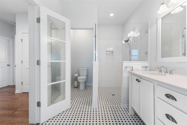 bathroom with a tile shower, vanity, hardwood / wood-style floors, and toilet