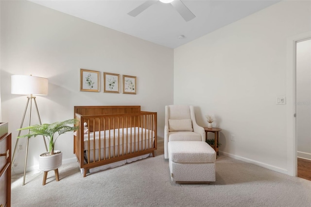 bedroom featuring a crib, carpet, and ceiling fan