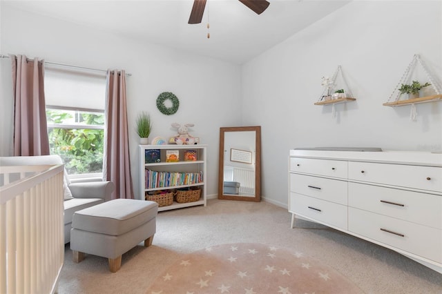 carpeted bedroom with a nursery area and ceiling fan