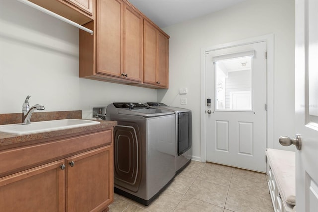 clothes washing area with light tile patterned floors, cabinets, sink, and washing machine and clothes dryer