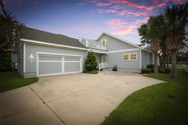 view of front of home with a garage, a balcony, and a lawn