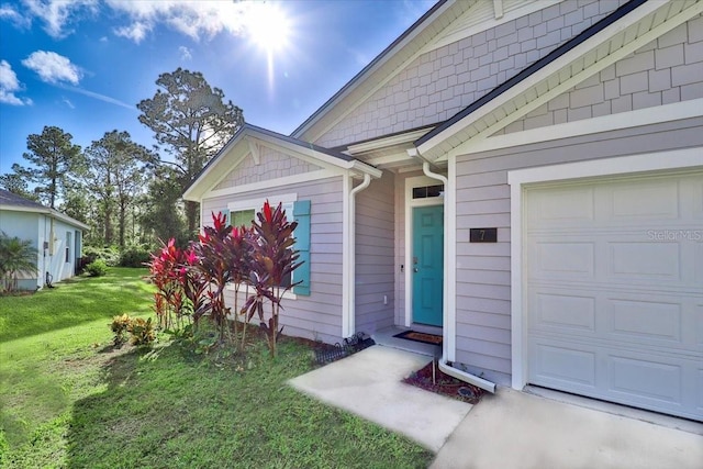 view of exterior entry featuring a garage and a lawn