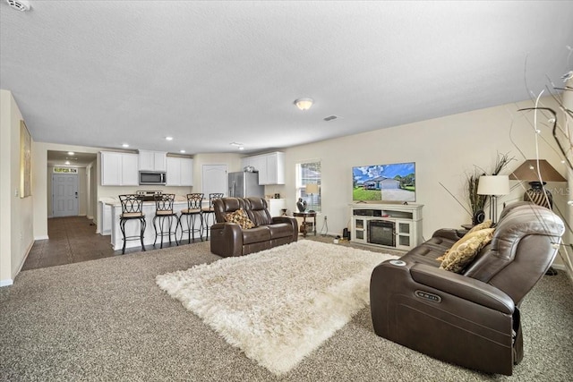 living room featuring a textured ceiling and dark colored carpet