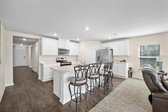 kitchen with stainless steel appliances, a breakfast bar, white cabinets, dark hardwood / wood-style flooring, and a textured ceiling