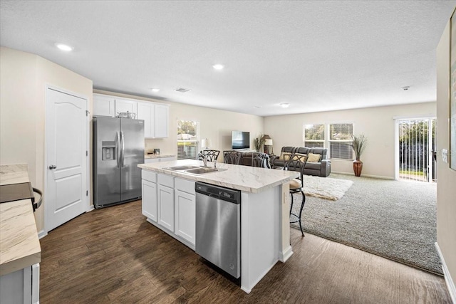 kitchen with white cabinets, appliances with stainless steel finishes, sink, and a kitchen island with sink