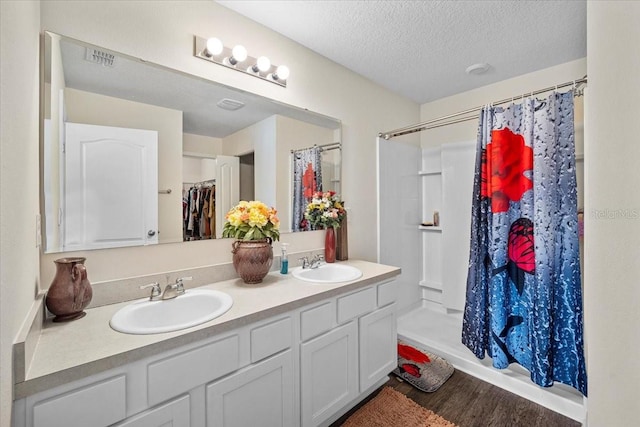 bathroom with a textured ceiling, hardwood / wood-style floors, vanity, and a shower with curtain