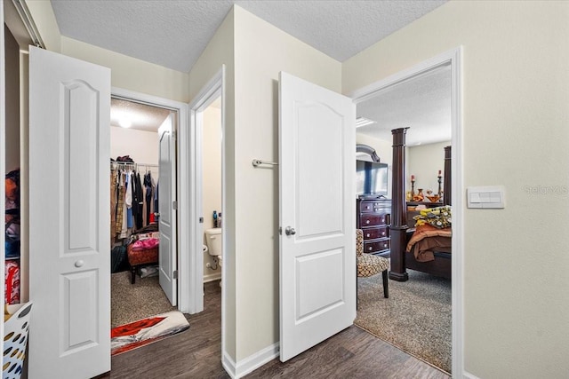 hallway with a textured ceiling and dark wood-type flooring