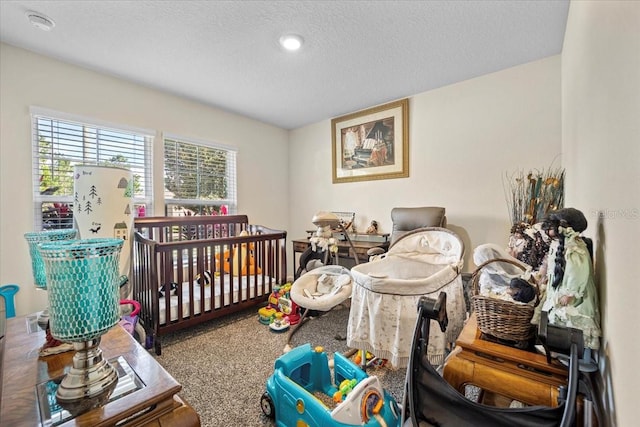 carpeted bedroom with a nursery area and a textured ceiling