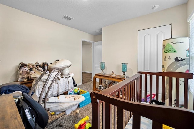 carpeted bedroom featuring a crib and a textured ceiling