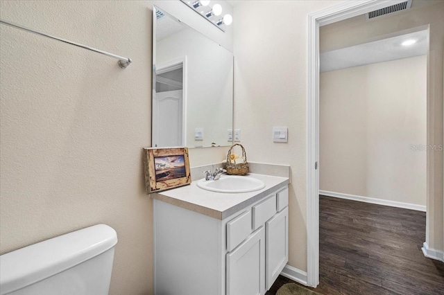 bathroom with hardwood / wood-style floors, vanity, and toilet