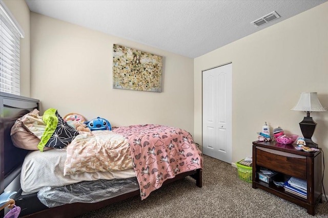 bedroom with a closet, carpet flooring, and a textured ceiling