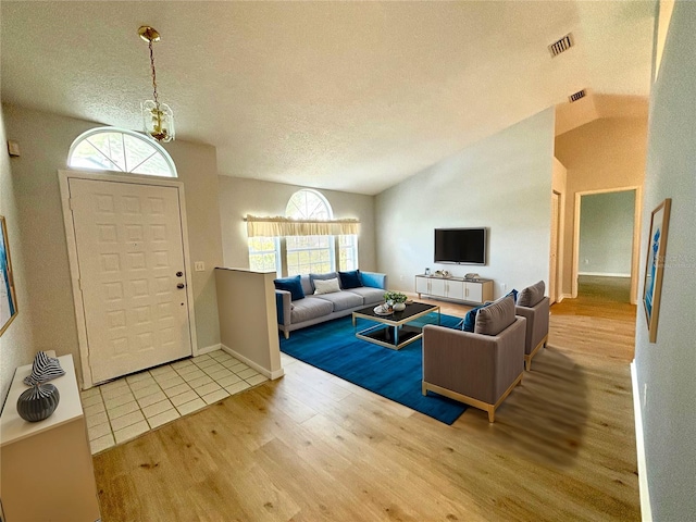 entrance foyer with a textured ceiling, lofted ceiling, a wealth of natural light, and hardwood / wood-style floors