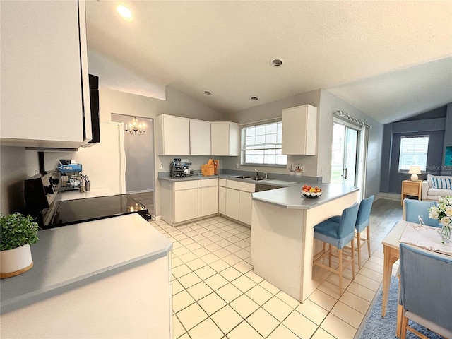 kitchen featuring black range, sink, lofted ceiling, white cabinets, and light tile patterned floors