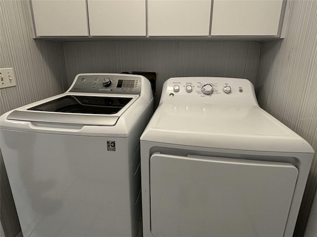 clothes washing area with washer and dryer and cabinets