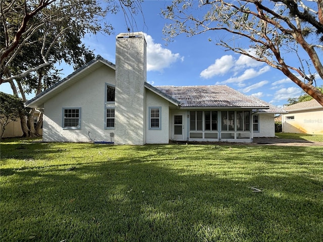 rear view of property featuring a yard and a sunroom