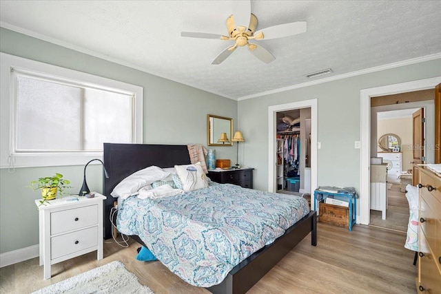 bedroom featuring ceiling fan, a textured ceiling, light hardwood / wood-style flooring, a walk in closet, and a closet