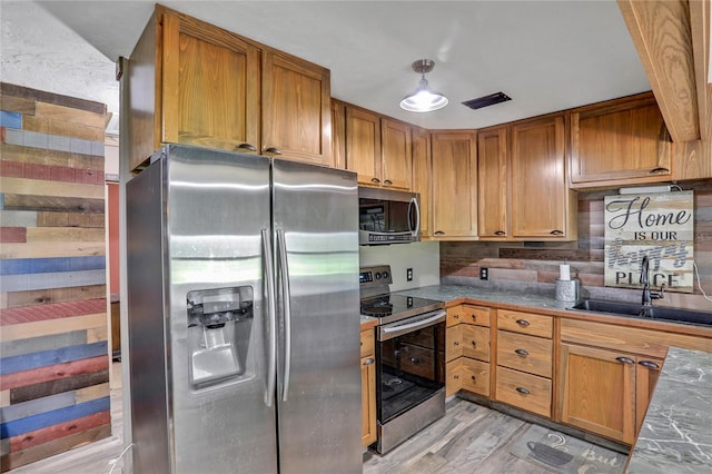 kitchen with backsplash, sink, stainless steel appliances, and light hardwood / wood-style flooring